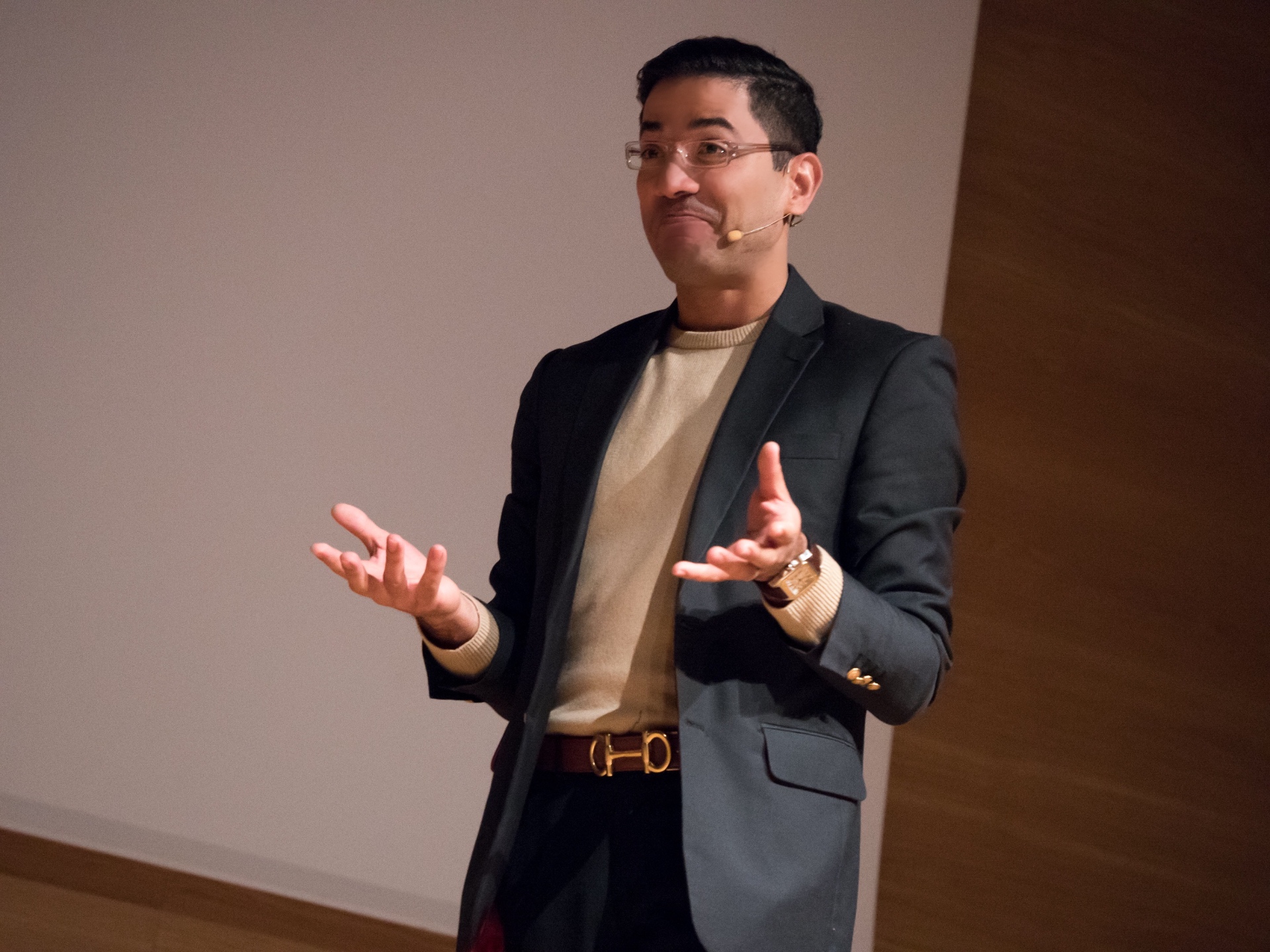 José Namén gesturing with open hands while presenting on stage.